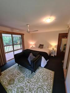 ein Schlafzimmer mit einem Bett und einem Sofa darin in der Unterkunft Bird Songs Getaway Accommodation in Cabbage Tree Creek