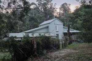 a white house with a fence in front of it at Bird Songs Getaway Accommodation in Cabbage Tree Creek
