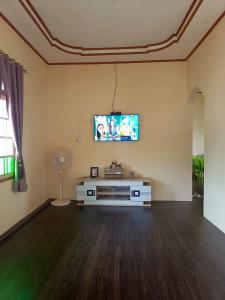 a living room with a flat screen tv on a wall at SUNGAI TANANG Homestay Syariah in Padangluar