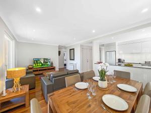 a living room with a dining table and a kitchen at Villa Sera in Pokolbin