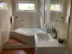 Baño blanco con bañera y lavamanos en Southern Grampians Cottages, en Dunkeld