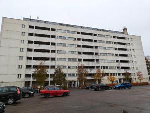 un grande edificio bianco con auto parcheggiate in un parcheggio di Nest Hostel a Turku