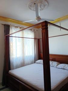 a bedroom with a canopy bed and a window at Mombasa , Kenya 2 bedroom Master Ensuite in Mombasa