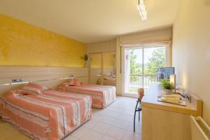 1 dormitorio con 2 camas, escritorio y ventana en Hotel Sausa, en Vilafreser