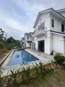ein weißes Haus mit einem Pool davor in der Unterkunft Sun Villa Thanh Liên Wyndham Vườn Vua Resort & Villas in Ðồng Phú