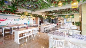 Ganghwa Elijah Resort في انشيون: مطعم بطاولات بيضاء وكراسي ونباتات