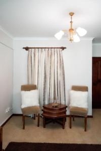 - deux chaises et une table dans une chambre avec fenêtre dans l'établissement Olive Home Arusha, à Nasulo