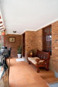 une terrasse couverte avec un banc et un mur en briques dans l'établissement Olive Home Arusha, à Nasulo