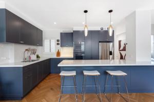 a kitchen with blue cabinets and white counters and stools at Potts Point l 2 Bedroom Stylish Retreat in Sydney