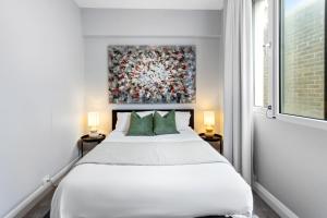 a bedroom with a white bed and a painting on the wall at Potts Point l 2 Bedroom Stylish Retreat in Sydney