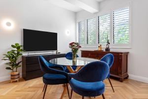 a dining room with blue chairs and a table and a tv at Potts Point l 2 Bedroom Stylish Retreat in Sydney