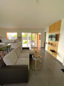 ein Wohnzimmer mit einem Sofa und einem Tisch in der Unterkunft Évasion tropicale Villa de rêve avec piscine à Petit Bourg in Petit-Bourg