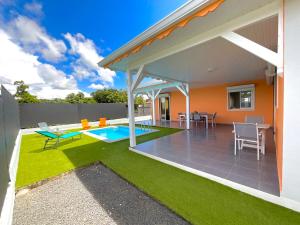 einen Hinterhof mit einem Pool und einem Haus in der Unterkunft Évasion tropicale Villa de rêve avec piscine à Petit Bourg in Petit-Bourg