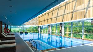 a large swimming pool in a building with windows at Wanda Realm Heshan in Jiangmen