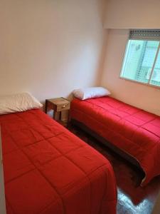 a room with two red beds and a window at Insuperable depto en san telmo. in Buenos Aires