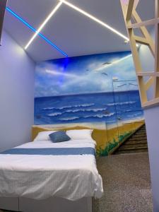 - une chambre avec un lit et une peinture sur l'océan dans l'établissement 澎湖串門子輕旅民宿Penghu Chuanmenzi Light B&B, à Magong