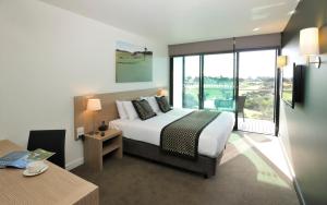 a hotel room with a bed and a large window at Mercure Portsea & Portsea Golf Club in Portsea