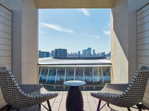 two chairs and a table on a balcony with a view of the city at Mitsui Garden Hotel Jingugaien Tokyo Premier in Tokyo