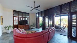 sala de estar con sofá rojo y TV en Wongalinga, en Mission Beach