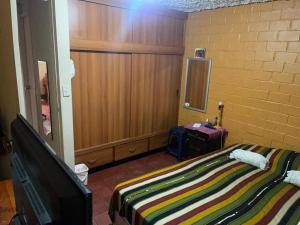 a bedroom with a bed and a tv and a wall at comfortable and spacious house with garage in Amatitlán