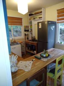 eine Küche mit einem Holztisch und einem Kühlschrank in der Unterkunft Donde la Euli in Pitrufquén