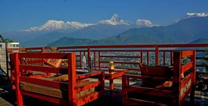 balcón con mesa, sillas y montañas en Hotel Himalayan Home Pokhara Lamagaun 10 minute from Lakeside by car, en Pokhara