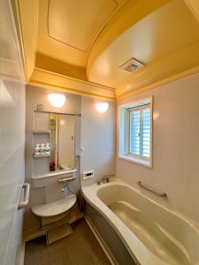 a bathroom with a tub and a sink and a window at 黒まめ庵 in Tamba