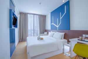 ジャカルタにある1O1 URBAN Jakarta Pemudaの白いベッドとデスクが備わるホテルルームです。