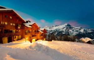 um alojamento de esqui na neve com montanhas ao fundo em LES PETITS ETERLOUS Appartement T3 36m2 à Puy St Vincent 1800 Alpes du sud 6 personnes parking privé couvert em Puy-Saint-Vincent