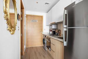 a kitchen with a stainless steel refrigerator and wooden cabinets at Perfect Getaway Studio APT Aura by Aziza in Dubai