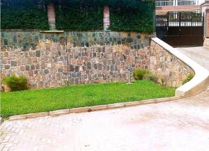 una pared de piedra con una zona de césped junto a una acera en Heritage Accommodation, en Kigali