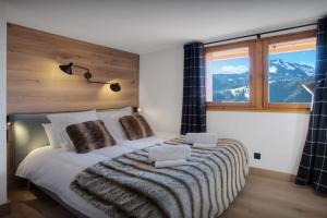 a bedroom with a large bed with a large window at Chalet Manoe - OVO Network in Manigod