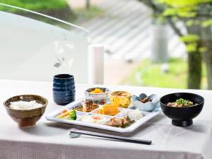 een bord eten op een tafel met kommen eten bij Mitsui Garden Hotel Chiba in Chiba