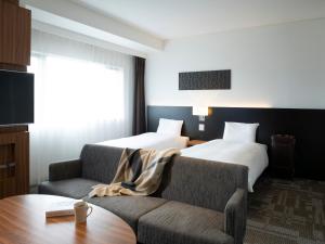 a hotel room with a couch and a bed at Mitsui Garden Hotel Chiba in Chiba