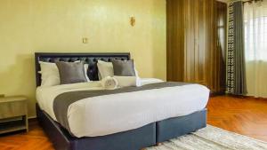 1 dormitorio con 1 cama grande con almohadas blancas y grises en Taliah Homestays, en Nanyuki