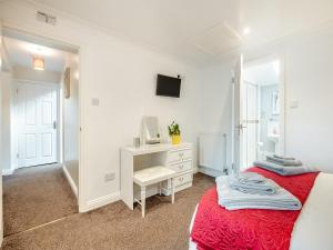 a white bedroom with a bed and a desk at Cwtch Corner in New Milton