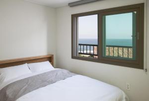 a bedroom with a bed and a window with a view at Jeju Aria Pension in Jeju