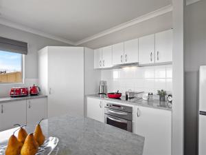 a kitchen with white cabinets and a counter top at The Dunes Pet Friendly Beachfront Family Retreat Busselton in Busselton