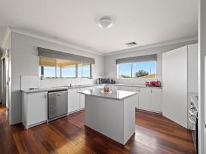 uma cozinha com electrodomésticos brancos e pisos em madeira em The Dunes Pet Friendly Beachfront Family Retreat Busselton em Busselton