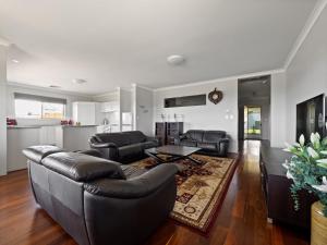 een woonkamer met een leren bank en een tafel bij The Dunes Pet Friendly Beachfront Family Retreat Busselton in Busselton