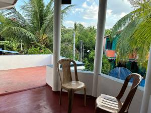 Duas cadeiras sentadas numa varanda com palmeiras em TPK Trinco Holiday Inn em Trincomalee