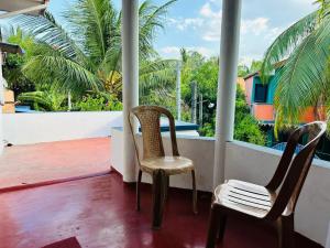 two chairs on a balcony with palm trees at TPK Trinco Holiday Inn in Trincomalee