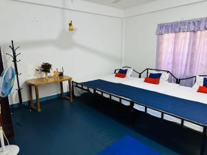 two beds in a room with blue floors and a table at TPK Trinco Holiday Inn in Trincomalee