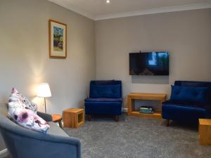 a living room with two blue chairs and a flat screen tv at Havre De Calme in Halstead