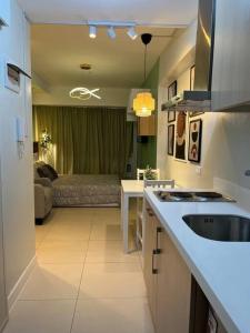 a kitchen with a sink and a living room at Relaxing and Cozy Unit at The Residences in Manila