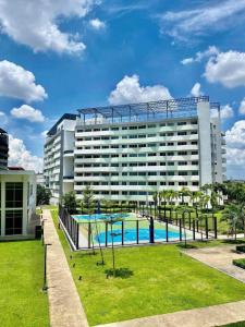 a large building with a swimming pool in front of it at Relaxing and Cozy Unit at The Residences in Manila