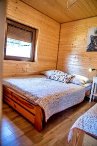 a bedroom with a bed in a wooden cabin at Dobra Miejscówka 80 m od Jeziora Solińskigo Sauna Jacuzzi in Zawóz