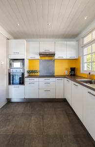 a kitchen with white cabinets and yellow walls at Toahotu estate one of a kind villa in Tahiti Iti pool and view - 15 pers in Vairao