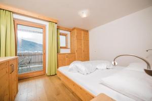 um quarto com uma cama e uma grande janela em Pichlerhof Apt 4 em Valle Di Casies