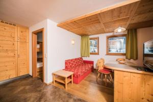 uma sala de estar com um sofá vermelho e uma mesa em Pichlerhof Apt 4 em Valle Di Casies